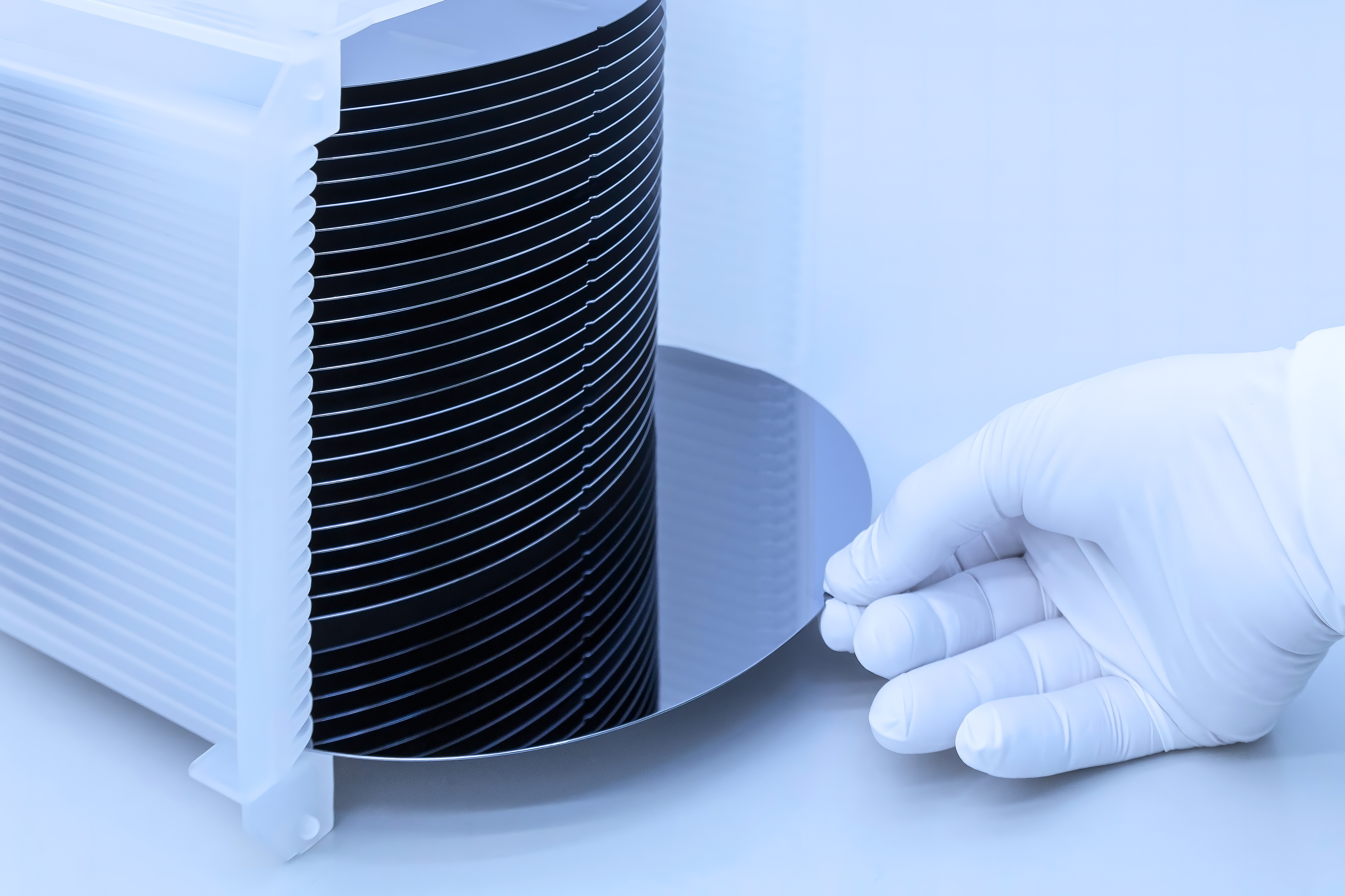 Silicon wafer inspection. A batch of silicon wafers packed in a plastic storage box in the clean room of a semiconductor foundry ready for microchip production. Banner.
